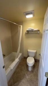 a bathroom with a toilet and a tub and a sink at Garden Inn and Suites Glendora in Glendora
