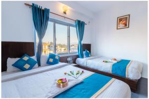 2 Betten in einem Zimmer mit Fenster in der Unterkunft Hotel Tulip Pokhara Inn in Pokhara
