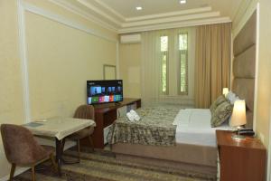 ein Hotelzimmer mit einem Bett und einem TV in der Unterkunft All Seasons Hotel Baku in Baku