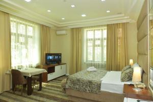 ein Hotelzimmer mit einem Bett, einem Tisch und einem TV in der Unterkunft All Seasons Hotel Baku in Baku