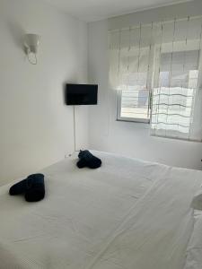 una camera da letto con un letto bianco con due sacchi neri sopra di Apartamento Es Calo (Edificio Cavall de Llevant) a Es Caló de Sant Agustí
