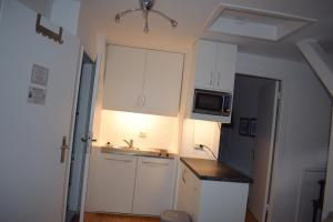 a small kitchen with white cabinets and a microwave at Privatzimmer Hamburg Alsterdorf in Hamburg