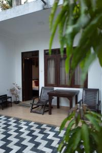 a porch with two chairs and a table and a checkered floor at Weligama Watergate in Weligama