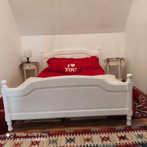 a white bed with a red pillow on it at Casa Haiducilor Brasov in Braşov