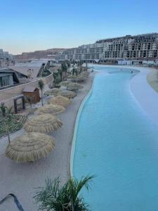 une piscine avec des parasols en paille et un complexe hôtelier dans l'établissement chalet 2 bedroom il Monte Galala al ain sokhna CH161-1-4, à Ain Sokhna 24 autres photos