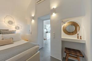 Habitación blanca con cama y espejo en Helianthus Suites- Caldera Caves, en Oia