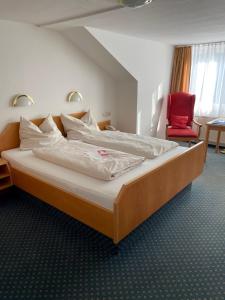 ein großes Bett in einem Hotelzimmer mit einem roten Stuhl in der Unterkunft Kneipp-Bund Hotel Bad Wörishofen in Bad Wörishofen