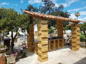 a stone pergola in a yard with trees at Terre di mare near the sandy beach with pool, parking & wifi in Fontane Bianche