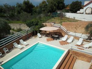 a swimming pool with chairs and a table and a umbrella at Terre di mare near the sandy beach with pool, parking & wifi in Fontane Bianche