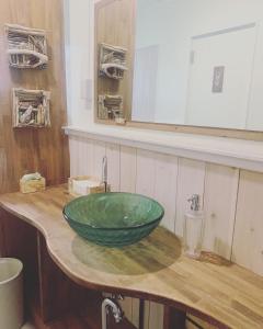 ein Waschbecken im Bad mit einer grünen Schüssel auf einer Holztheke in der Unterkunft Kanzaki Beach House 