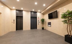 korytarz z dwoma drzwiami i telewizorem na ścianie w obiekcie Hotel Legit w mieście Hiroszima