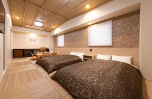 広島市にあるHotel Legitのベッド2台、テーブル、ソファが備わる客室です。
