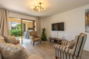 uma sala de estar com um sofá e cadeiras e uma televisão em 67 The Shades - Luxury Apartment in Umhlanga - Airconditioning throughout and Inverter em Durban
