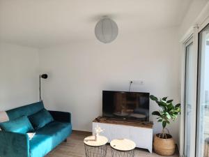 ein Wohnzimmer mit einem blauen Sofa und einem TV in der Unterkunft Gîte Les amoureux de la Baie in Favières
