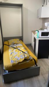 1 cama con edredón amarillo en la cocina en Ambert CentreVille La Studette tout confort, en Ambert