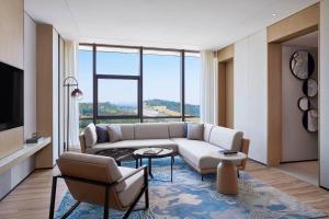 a living room with a couch and a large window at Courtyard by Marriott Qinhuangdao West in Qinhuangdao