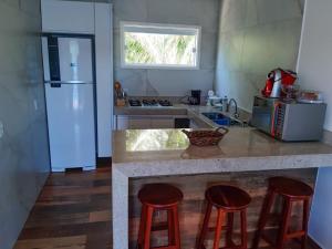 a kitchen with a counter with stools and a refrigerator at Casa Arraial do Cabo Beachfront in Arraial do Cabo