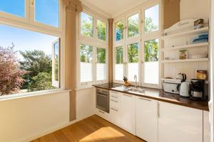 uma cozinha com armários brancos e janelas em Villa Saphira App 09 em Heringsdorf