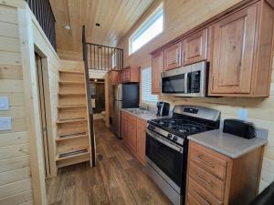 a kitchen with wooden cabinets and a stove and microwave at 036 Tiny Home nr Grand Canyon South Rim Sleeps 8 - Full Kitchen in Valle