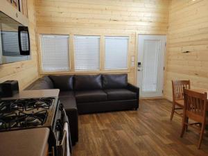 a living room with a black couch and a stove at 036 Tiny Home nr Grand Canyon South Rim Sleeps 8 - Full Kitchen in Valle