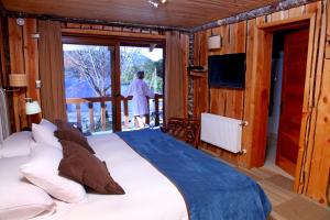 1 dormitorio con 1 cama grande y balcón en Huilo Huilo Marina del Fuy Lodge, en Reserva Biológica Huilo Huilo