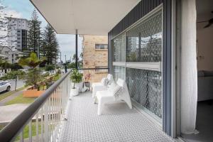 a balcony with white chairs and a large window at Freddies - pet friendly! last minute discount! in Gold Coast