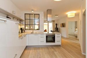 eine große Küche mit weißen Schränken und ein Wohnzimmer in der Unterkunft Villa Bettina, App. 01 in Heringsdorf