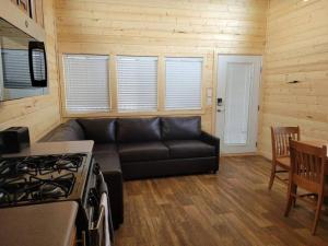 a living room with a black couch and a stove at 037 Tiny Home nr Grand Canyon South Rim Sleeps 8 in Valle