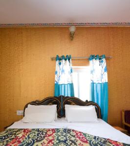 a bedroom with a bed with blue curtains and a window at Hotel Prem Villas Pushkar in Pushkar