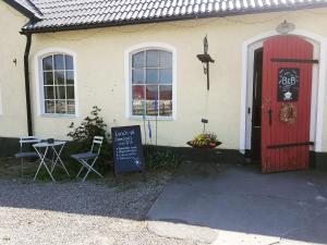 une maison avec une porte rouge et un panneau devant elle dans l'établissement Smedjan Mat & Logi, à Östra Ingelstad