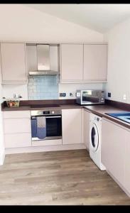 a kitchen with white cabinets and a washing machine at The Inn Keeper in Cranswick