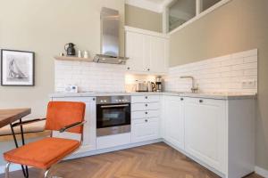 una cucina con armadi bianchi e una sedia arancione di Villa Bellevue App 02 a Heringsdorf