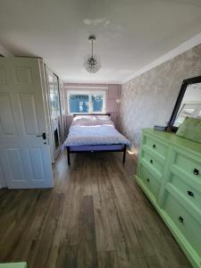 a bedroom with a bed and a dresser and a mirror at Alis haven in Pegswood