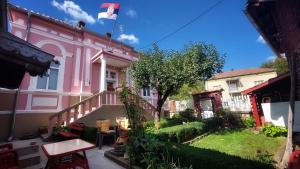 ein rosa Haus mit einem Garten davor in der Unterkunft Vila Milenovic Rajacke Pivnice in Rajac