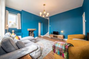 a living room with blue walls and a couch and chairs at Corner Cottage in Matlock