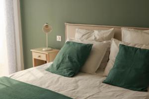 - un lit avec des oreillers verts et blancs et une lampe dans l'établissement Gîtes de Lauvergnac - Maisons 2 Ch, 2 SdB, à La Turballe