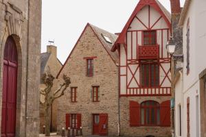 ein altes Gebäude mit roten Rollläden auf einer Straße in der Unterkunft Gîtes de Lauvergnac - Maisons 2 Ch, 2 SdB in La Turballe