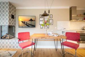cocina con mesa de madera y sillas rojas en Villa Bellevue App 06, en Heringsdorf