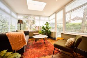 a living room with a couch and chairs and windows at Little Hayes, Lyndhurst in Lyndhurst