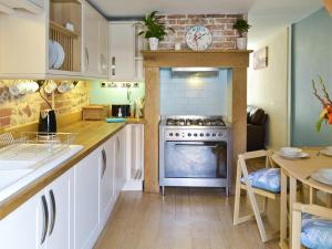a kitchen with white cabinets and a stove and a table at Seashells in Cromer