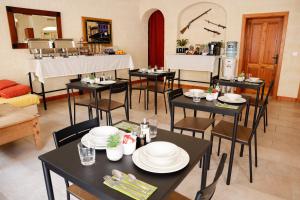 a restaurant with black tables and chairs and a kitchen at Rosehill B&B in Xagħra