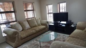 a living room with a couch and a tv at Relaxing Holiday Home in Phuthaditjhaba