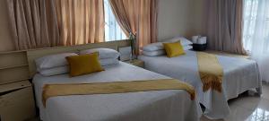 una habitación de hotel con dos camas con almohadas amarillas en Relaxing Holiday Home, en Phuthaditjhaba