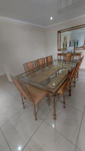 a dining room with a glass table and chairs at Relaxing Holiday Home in Phuthaditjhaba