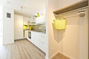 uma cozinha com armários brancos e um cesto amarelo na parede em Ostseedomizil Bansin App 2 1 em Bansin