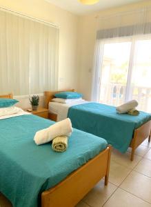 a bedroom with two beds with blue sheets and a window at Villa Agnes in Ayia Napa