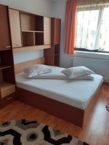 um quarto com uma cama grande com lençóis brancos e almofadas em Casa Miruna em Poiana Negrii