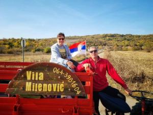 Zwei Männer sitzen auf dem Rücksitz eines roten Trucks in der Unterkunft Vila Milenovic Rajacke Pivnice in Rajac