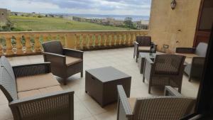 a patio with chairs and tables and a balcony at Warda Accommodation in Xewkija