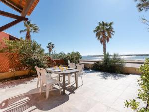 a table and chairs on a patio with the beach at Villa Gruissan, 3 pièces, 6 personnes - FR-1-409A-20 in Gruissan